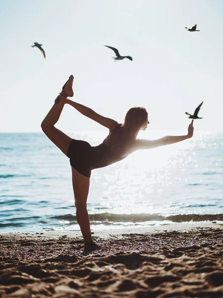 Bella giovane donna che pratica yoga mattutino sulla spiaggia di sabbia del mare. Surya Namaskar - Saluti al sole . — Foto Stock