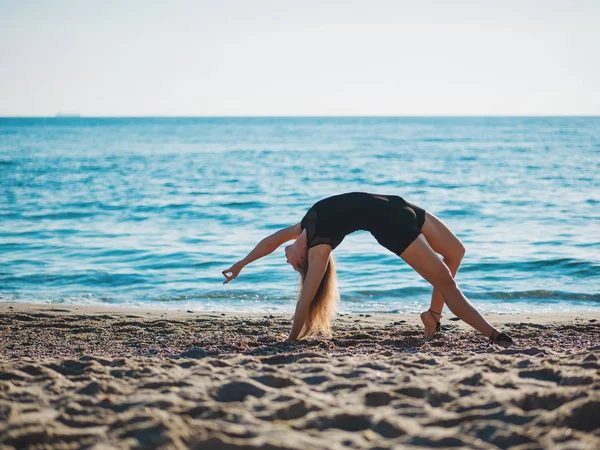 Bella giovane donna che pratica yoga mattutino sulla spiaggia di sabbia del mare. Surya Namaskar - Saluti al sole . — Foto Stock