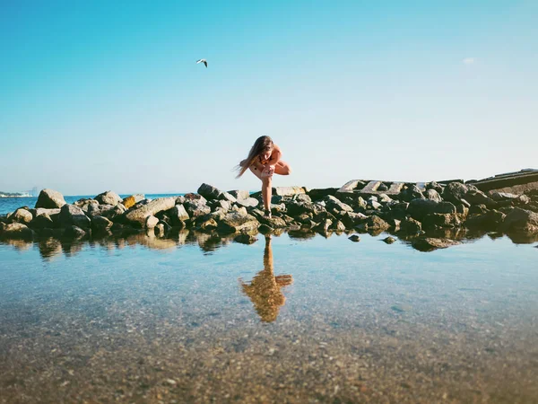 Mujer joven caucásica en traje de baño practicando yoga en agua de mar, lago o río. Hermoso reflejo. Asanas complejas, equilibrio. Fitness, deporte, yoga y estilo de vida saludable . — Foto de Stock