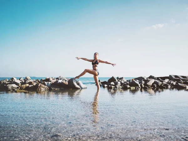 Fiatal kaukázusi nő fürdőruha gyakorló jóga a tengervíz, a tóra vagy a folyóra. Szép elmélkedés. Komplex ászanák, egyensúly. Fitness, sport, jóga és egészséges életmód fogalma. — Stock Fotó