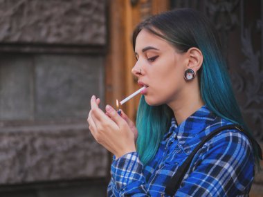 Genç punk kız ahşap kapının yanında Sigara İçilmeyen. Mavi boyalı saçlı hippi. Burun, Menekşe lensler, kulakları tüneller ve sıradışı saç modeli piercing ile kadın.