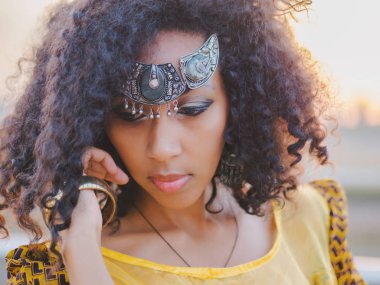Renkli sarı geleneksel kıyafet ve gülümseyen ve kamera yakın dans alnına gümüş crown genç Afro-Amerikan çingene kadın portresi. Kıvırcık saçlı kız seksi moda
