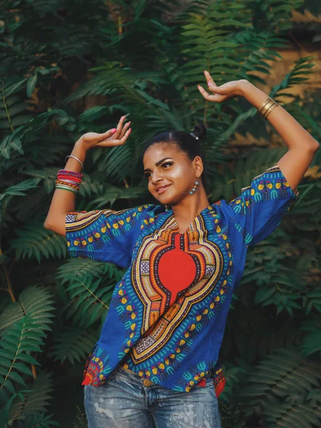 Afroamerikanerin tanzt im Freien. Multi-ethnische Mädchen tragen bunte Kleidung posiert, genießt die Natur. grüner tropischer Hintergrund — Stockfoto