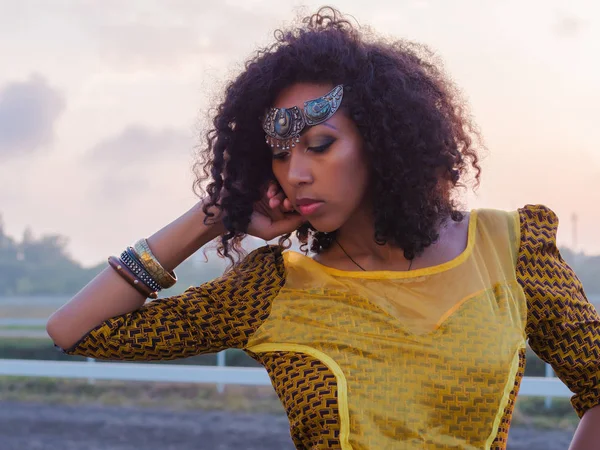 Porträt einer jungen afroamerikanischen Zigeunerin in farbenfroher gelber Tracht und silberner Krone auf der Stirn, die vor laufender Kamera lächelt und tanzt. sexy Mode Mädchen mit lockigem Haar — Stockfoto