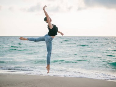 Dans eden balerin siyah üst ve kumlu plaj okyanus kot veya sabah denizde güzel bir sahne. Güzel esmer kadın uzanan pratik ve çalışmaları. Kopya alanı