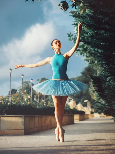 Bailarina dançante em tutu balé azul e ponto na rua europeia com árvores no verão ou outono. Jovem bela mulher morena praticando alongamento e exercícios . — Fotografia de Stock