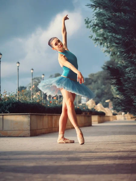 Bailarina dançante em tutu balé azul e ponto na rua europeia com árvores no verão ou outono. Jovem bela mulher morena praticando alongamento e exercícios . — Fotografia de Stock