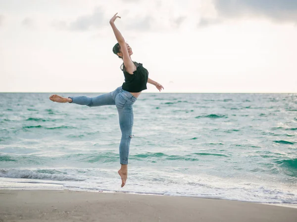 Dans eden balerin siyah üst ve kumlu plaj okyanus kot veya sabah denizde güzel bir sahne. Güzel esmer kadın uzanan pratik ve çalışmaları. Kopya alanı