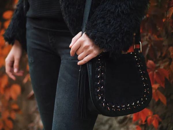 Uroda i moda. Stylowe modnej kobiety nosi czarne ubrania, trzymając ciemna torba torebka. Bliska strzał rąk w jesienny park. — Zdjęcie stockowe