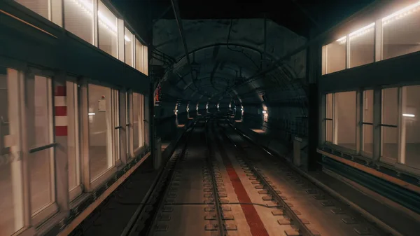 Vista del túnel del metro visto desde la ventana trasera del tren en movimiento. Tren subterráneo rápido sale de la moderna estación de metro . —  Fotos de Stock