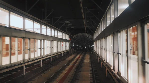 Vista del túnel del metro visto desde la ventana trasera del tren en movimiento. Tren subterráneo rápido sale de la moderna estación de metro . — Foto de Stock