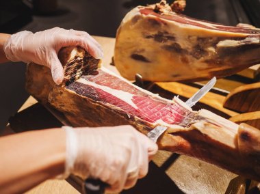 Eller eldiven Pazar veya mağaza içinde bir kadın geleneksel İspanyol jamon de bellota bir dilim kes. Et yakın çekim.
