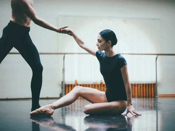 Giovane uomo che pratica nel balletto classico con giovane bella donna in abiti neri in palestra o nella sala da ballo. Coppia che salta ballando danza sensuale. Minimalismo interno , — Foto Stock