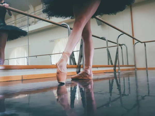 Ballerina in het ballet pointe strekt zich uit over barre in sportschool. Vrouw in dansstudio te beoefenen. Uit het werk van jonge meisje. — Stockfoto