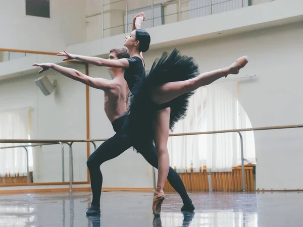 Jongeman oefenen in klassiek ballet met jonge mooie vrouw in zwarte tutu kleding in de sportschool. Minimalisme interieur, sensuele dans dansen. — Stockfoto