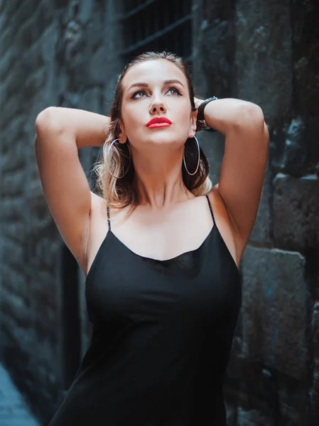Splendida donna bionda seducente in abito nero sexy e labbra rosse che camminano nel quartiere gotico di Barcellona. Bellezza naturale, ritratto femminile, sguardo seducente. Essere sicuri di sé . — Foto Stock