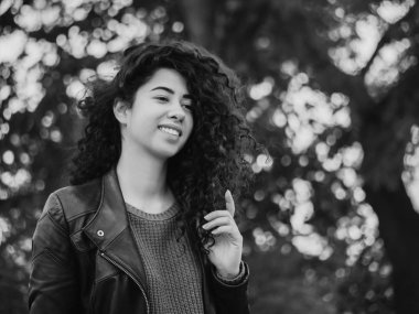 Mutlu genç kadının sokakta güzel kıvırcık saçlı siyah beyaz portre. İspanyol kız gülümseyerek