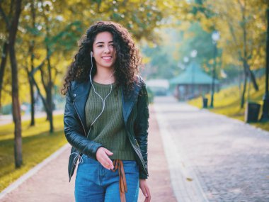 Kıvırcık saçlı kulaklık müzik dinlerken mutlu Afrikalı genç bayan. Dans ritim ve melodi sonbahar park boyunca şarkı İspanyol hippi kız.