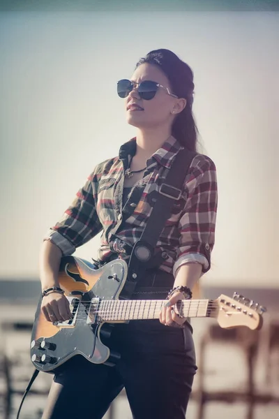Joven mujer sexy tocando la guitarra eléctrica. Artista de rock duro en el liman, playa lago . — Foto de Stock