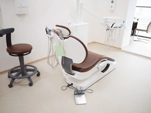 Сучасний стоматологічний кабінет. Коричневий шкіряний стілець та інші аксесуари, що використовуються стоматологами у білому медичному світлі — стокове фото