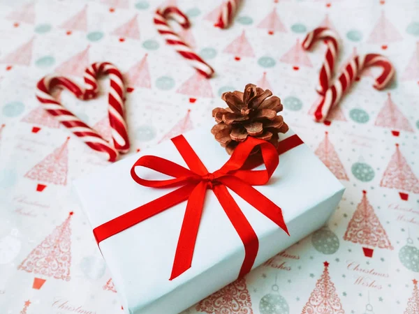 Fondo de Navidad alegre. Hermosa caja de regalo, piruletas tradicionales de bastón de caramelo, conos. Preparación para el concepto de vacaciones de invierno, vista superior — Foto de Stock