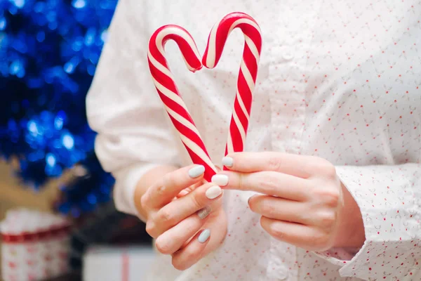 Donna che tiene bastoncini di zucchero nelle mani sullo sfondo dell'albero di Natale. Concetto di Capodanno. — Foto Stock