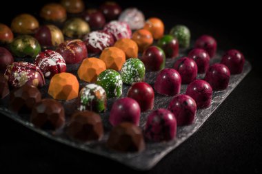 siyah arka plan üzerine izole lezzetli el yapımı çikolatalar. Şekerleme üretimi. renkli şeker, yemek pişirme sanatı.