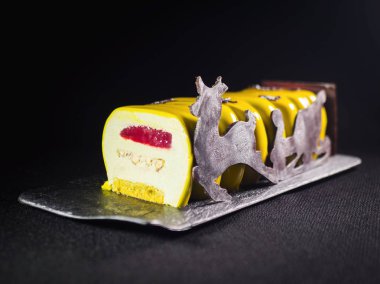 Çağdaş pasta sarı ayna sır ile kaplı ve koyu arka plan üzerinde çikolata reindeers elemanları ile dekore edilmiş.