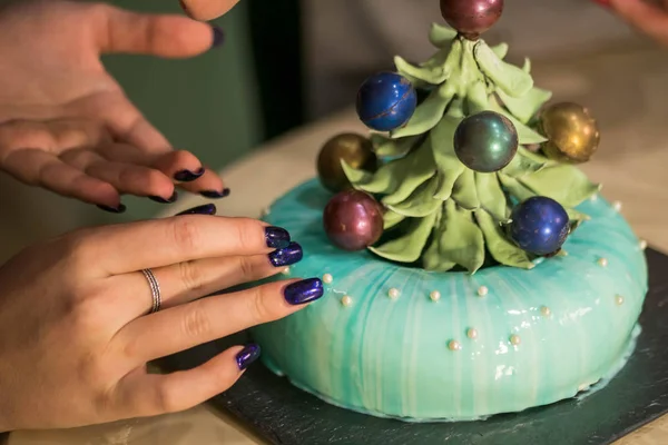 Colorata ciliegina sulla torta. Torta di mousse francese moderna con smalto a specchio. Donna mani decorazione dessert con albero di Natale al cioccolato. Arte culinaria . — Foto Stock