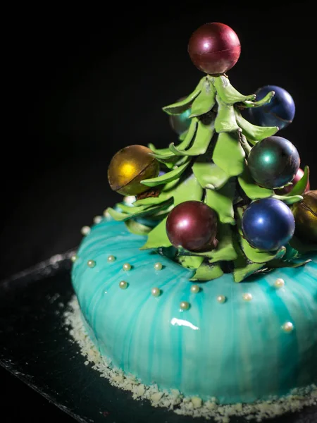 Contemporary Cake covered with blue chocolate mirror glaze and decorated with chocolate elements of Christmas tree, on dark background. — Stock Photo, Image