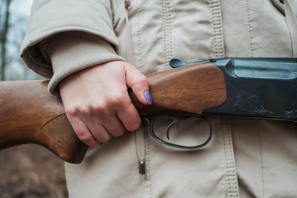 Cacciatrice in abiti caldi con pistola. Ragazza a caccia nella foresta tenendo il fucile da vicino . — Foto Stock