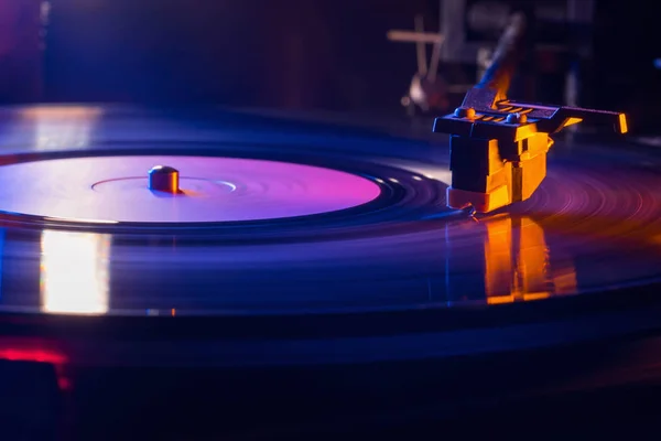 Retro-gestileerde film kijk van een draaiende record vinyl speler. Close-up. Zijaanzicht. Kleurrijke film met neon licht — Stockfoto