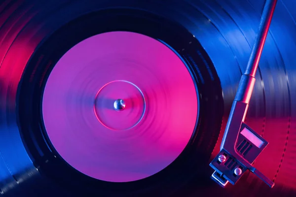 A retro-styled spinning record vinyl player. Vintage shot of old gramophone, playing close up. Beautiful colorful movie. Neon violet led light. — Stock Photo, Image