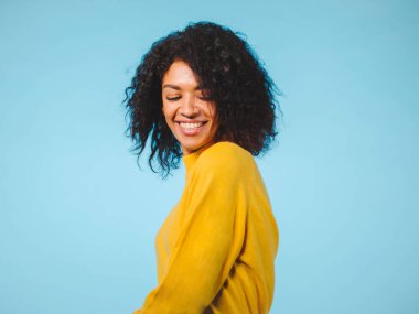 Üzerinde mavi arka plan izole gülen Afrikalı-Amerikalı kadın portresi kapatın. Sarı aşınmaya studio poz kız Mix yarıştı.