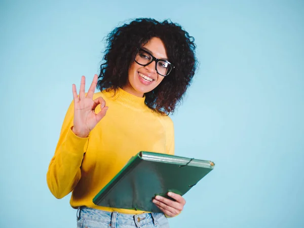 Personas, la educación, la escuela y el concepto de gesto - feliz afro-americana joven mujer mostrando signo ok sobre fondo azul —  Fotos de Stock