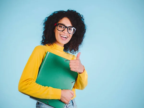 Ανθρώπους, εκπαίδευση, σχολείο και χειρονομία ιδέα - ευτυχισμένος afro Αμερικανός νεαρή γυναίκα γυαλιά δείχνει τους αντίχειρες επάνω σε μπλε φόντο — Φωτογραφία Αρχείου