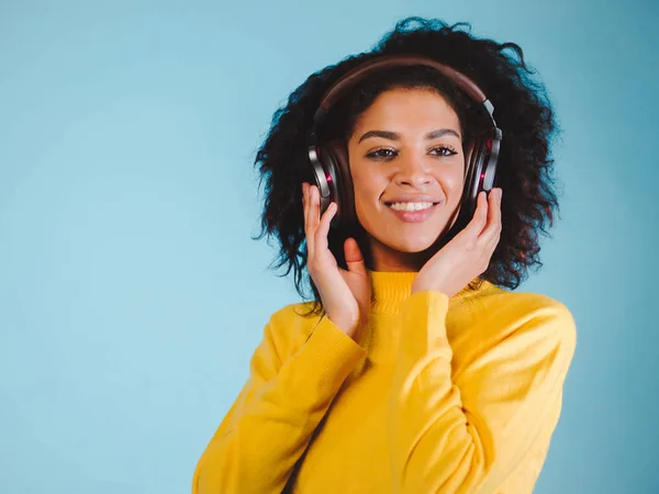 Концепція стилю життя. Портрет красивої афроамериканки радісно слухає музику на мобільному телефоні. Синій пастельний студійний фон. Копіювати пробіл . — стокове фото