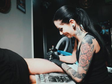 Kapatmak yukarıya-in sanatçı boya ile siyah dövme alma süreci gösterir. Atölyede çalışan usta. Genç adam bacak üzerinde dövme. Konsept: studio, müşteri iletişimi, özgürlük, sanat, genç