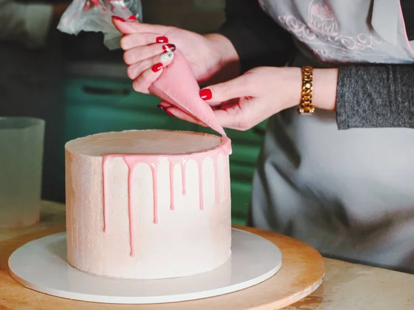 Oigenkännliga kvinna dekorera moussen glasyr tårta med ros, macarons, händerna detalj, fokus på kakan. DIY, sekvens, steg för steg, en del av serien. — Stockfoto