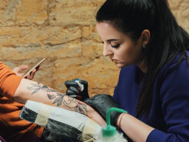 Menekşe giyim dövme yapma esmer kadın tattooer portresi müvekkili silah Studio ile kolu mans. Genç iş kadını atölye.