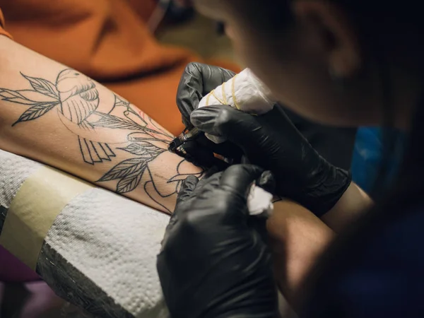 İş yerinde dövme sanatçısı. Siyah lateks eldiven dövme genç bir kadında Studio renkli resimli el mans. Yakın çekim. — Stok fotoğraf