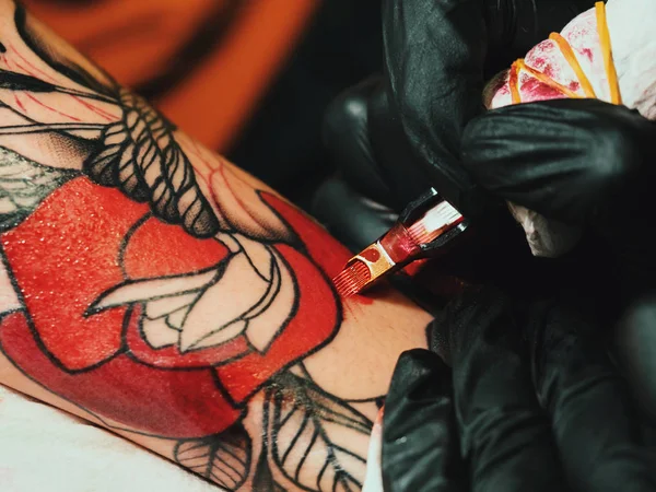 İş yerinde dövme sanatçısı. Siyah lateks eldiven dövme genç bir kadında Studio renkli resimli el mans. Makro. — Stok fotoğraf