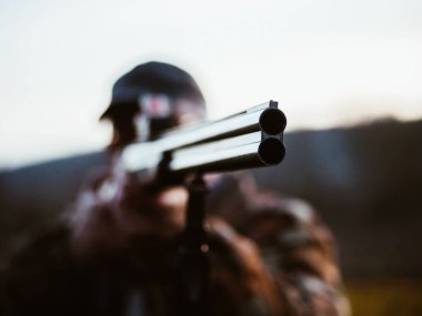 Çift namlulu av silahı kapatın. Sıcak palto giyiyor avcı adam tüfekle savaş düşman hedefler. Tanınmayan adam ormanda avlıyor. Varil üzerinde odaklanmak