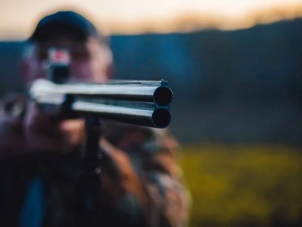 Homem caçador vestindo casaco quente atinge o inimigo no campo de batalha com rifle. Um homem irreconhecível caça na floresta. Foco no barril — Fotografia de Stock