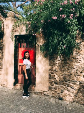 Kot pantolon ve spor ayakkabı eğilir bir duvara kırmızı kapıyla bir antik kent içinde giyinmiş genç bir kadın. Bir eski Avrupa şehir kadın bir gezgin. Yaşam tarzı portre