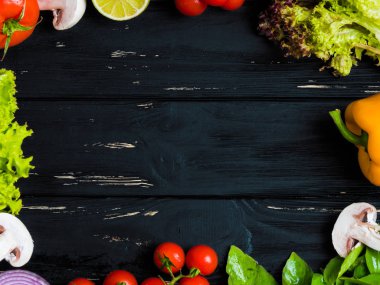 Taze çiftlik sebze, sarı kırmızı biber biber, fesleğen, domates, mantar, kırmızı soğan, limon, marul ile mutfak siyah eski püskü ahşap çerçeve arka plan. Gıda Üstten Görünüm.