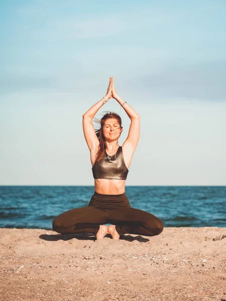Giovane bella donna sportiva in abbigliamento verde facendo yoga asana sulla spiaggia vicino all'acqua. Ragazza che pratica esercizi. Concetto sanitario . — Foto Stock