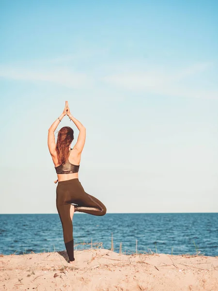 Giovane bella donna sportiva in abbigliamento verde facendo yoga asana sulla spiaggia di sabbia marina vicino all'acqua. Ragazza che pratica esercizi. Concetto di salute. Copia spazio . — Foto Stock