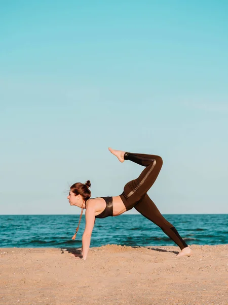 Fiatal, gyönyörű sportos nő csinál jóga asana a tengeri strand közelében a víz zöld ruha és a mala gyöngyök. Lány gyakorló gyakorlatok. Egészségügyi koncepció. — Stock Fotó