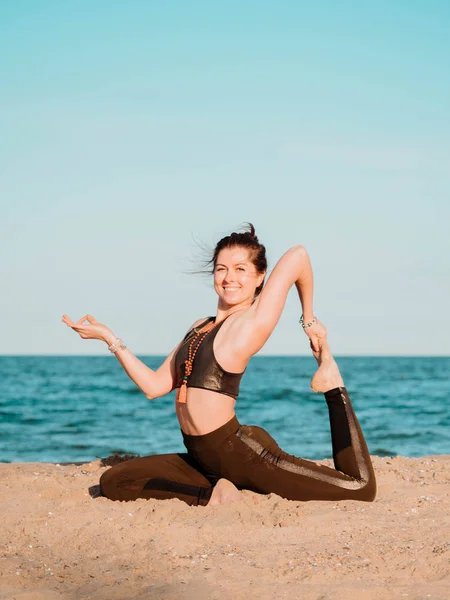Молода красива усміхнена жінка портрет робить йогу Асану на морському пляжі біля води. Дівчина практикує вправи. Концепція здоров'я . — стокове фото